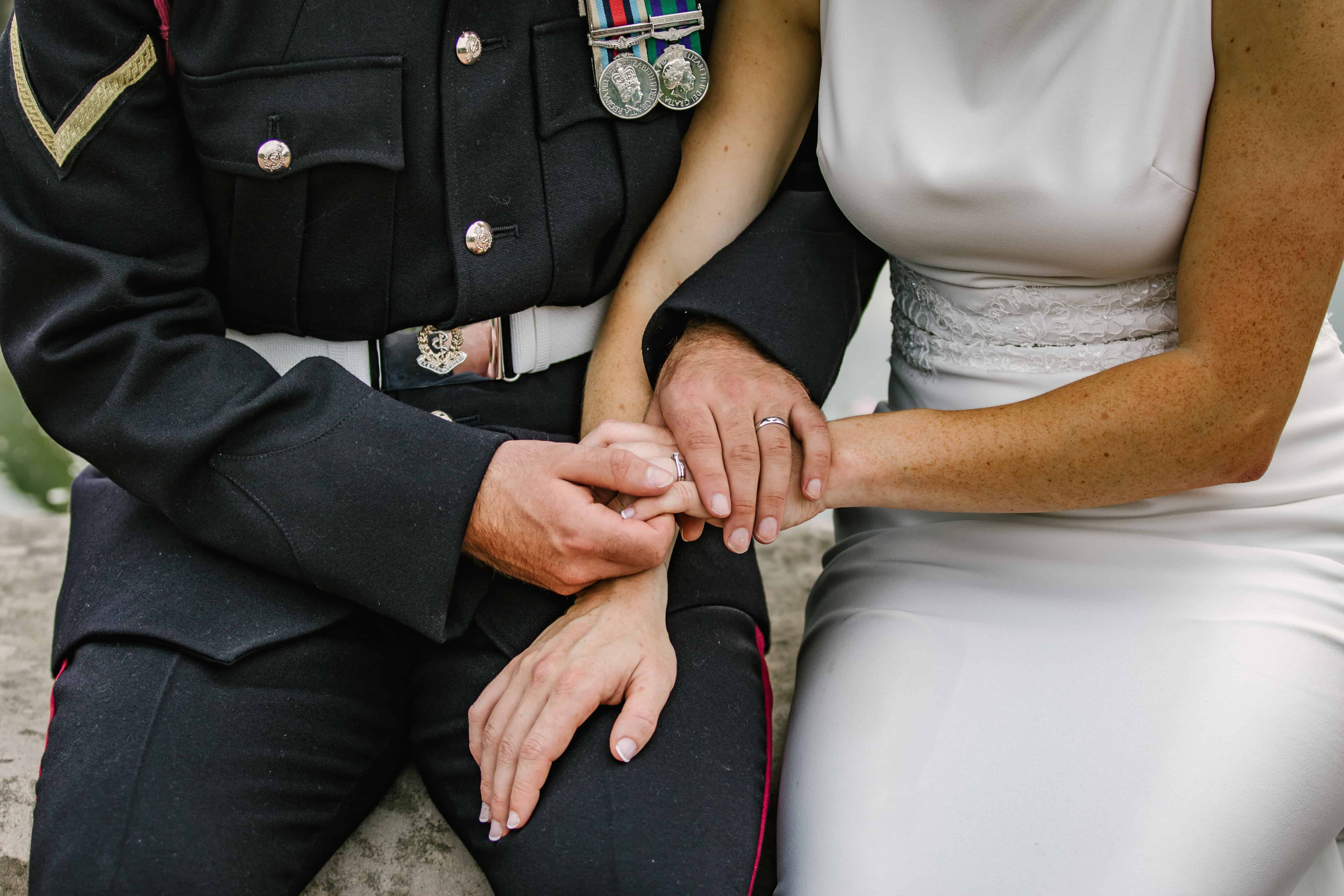 Close-up of bride and groom's hands and wedding rings — military wedding